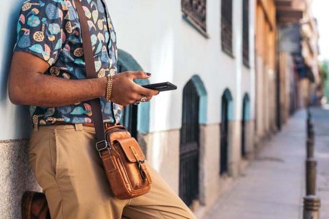 Stylish Black man using smartphone outdoors in the city