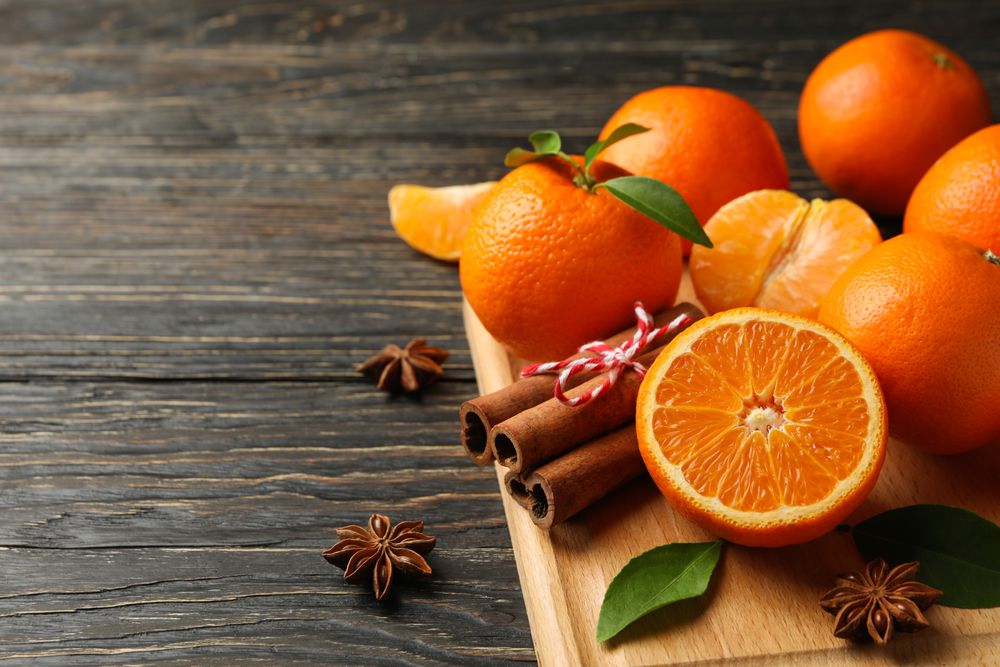 Board with mandarins and cinnamon on wooden background