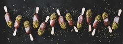 Ice cream chocolate pistachio popsicles, dark background, top view, wide composition