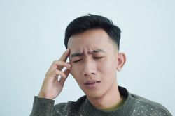 Asian young man touching temples with headache