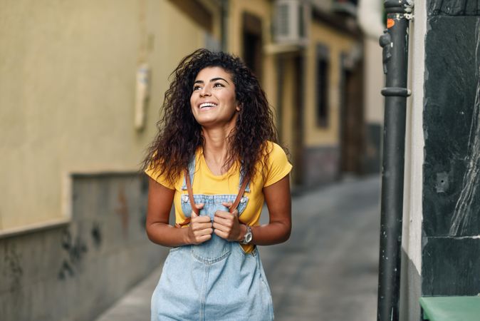Arab woman standing in the street in denim dress looking up