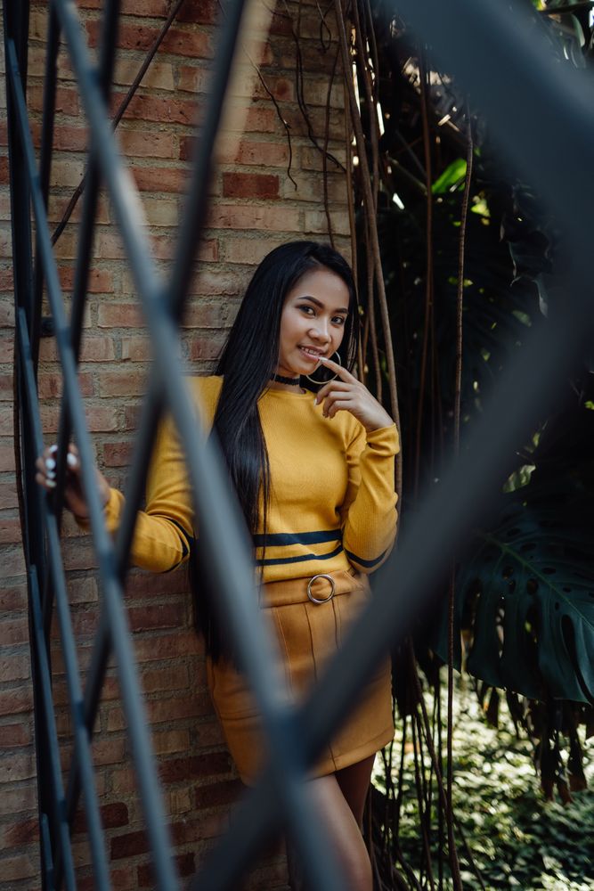 Smiling long haired Asian woman leaning on bricked wall