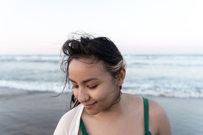 Portrait of a young Hispanic woman posing relaxed in front of the sea at the beach