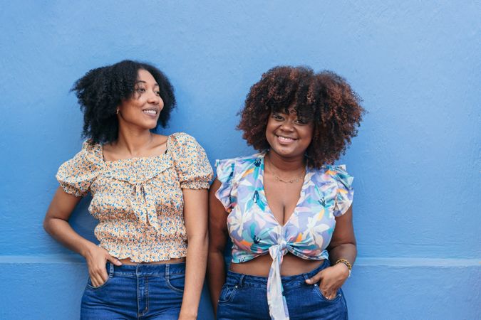 Two Black women standing in front of a wall.
