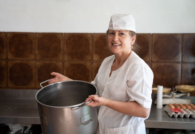 Baker woman smiling with a bakery pan next to egg cartons