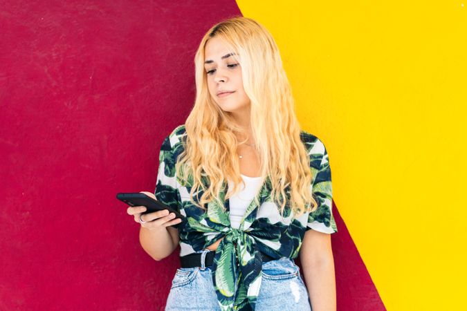 Blonde woman using mobile phone outdoors. Colorful background