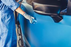 Man in blue jumpsuit opening door on blue car
