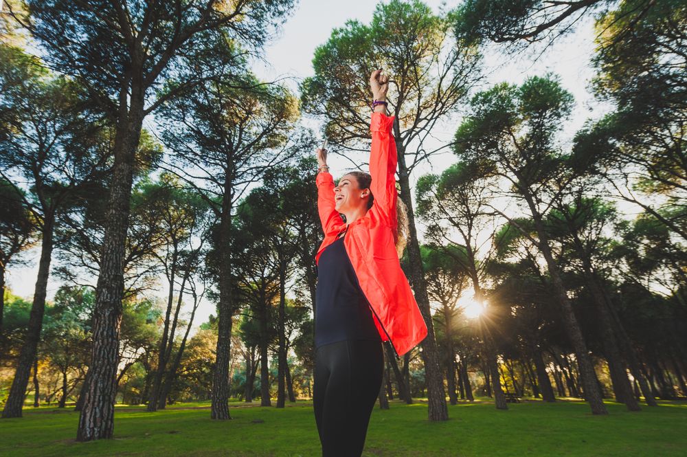 Excited sportswoman with arms raised in park