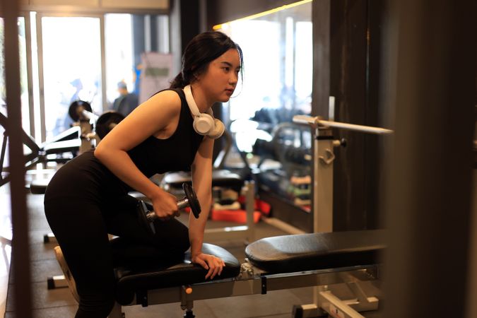 Young Female Training at the Gym Using Dumbbells While Listening to the Music