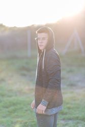 Teenage male in hoodie standing in field