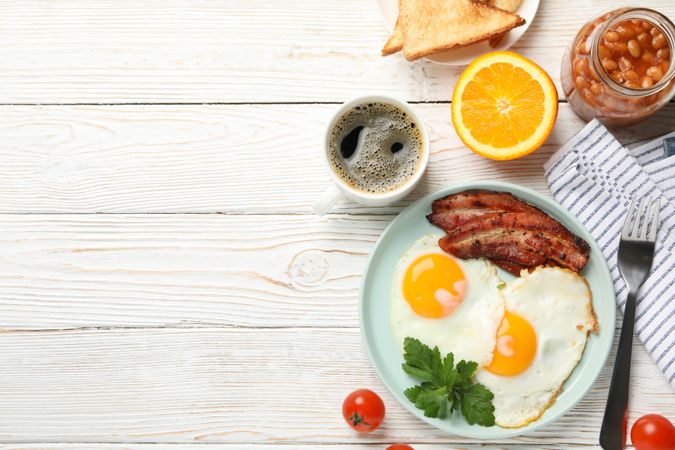 Full breakfast with eggs, beans, bacon, fruit and coffee, copy space