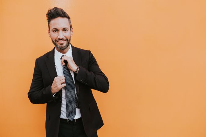 Adult stylish man in costume near orange wall