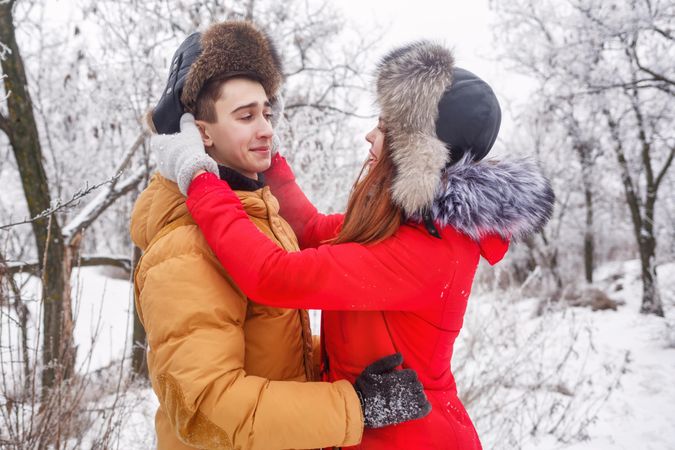 Teenage boy looking incredulously at girlfriend in wintery forest