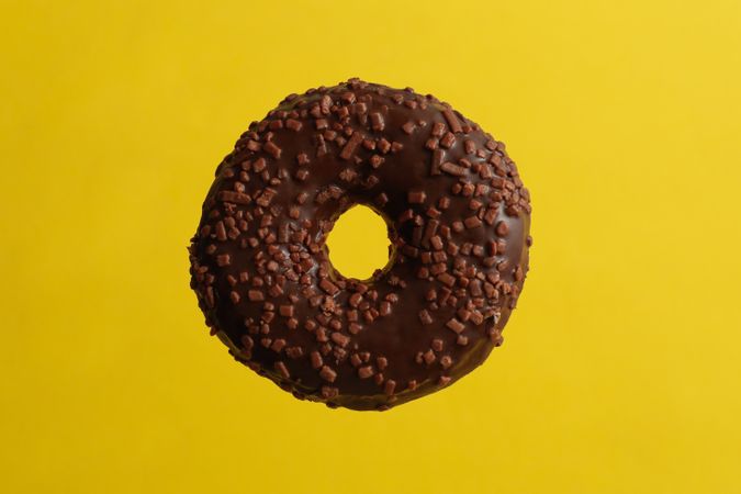One tasty chocolate donut on yellow background