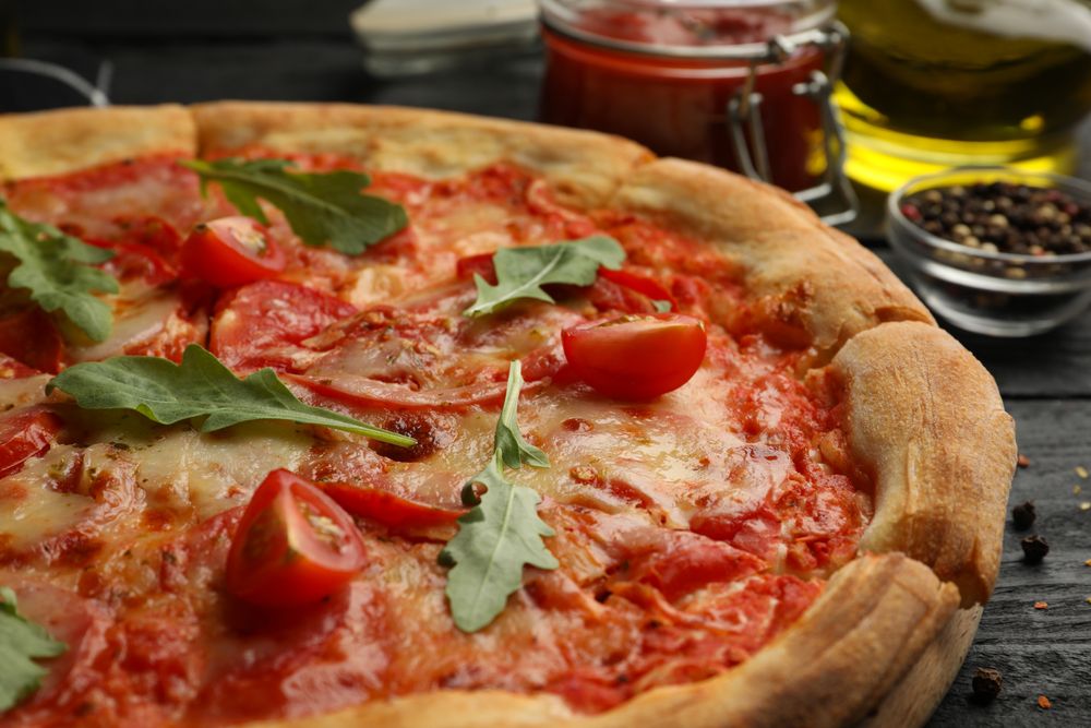 Tasty pizza and ingredients on wooden background