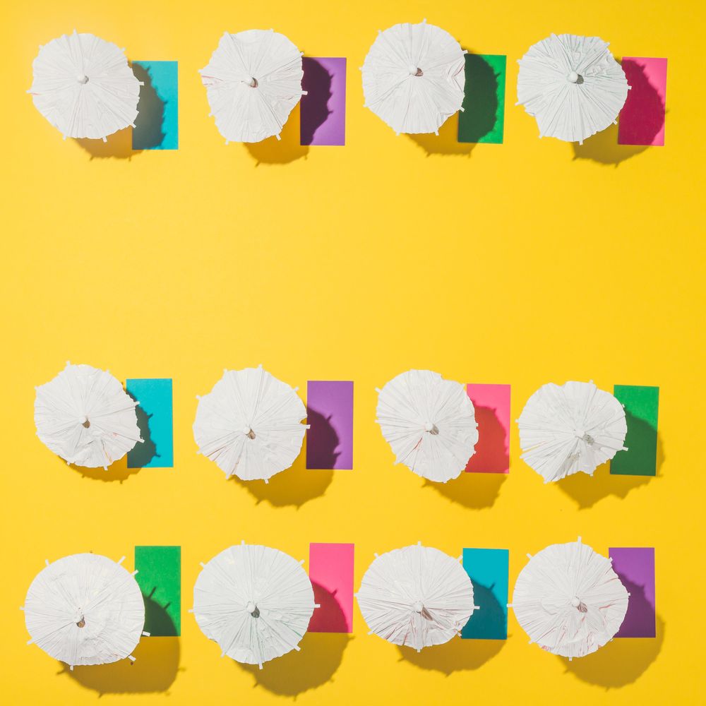 Pattern of sun umbrellas and multicolored towels in rows on yellow