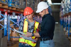 Male and female colleagues checking stock distribution before shipping