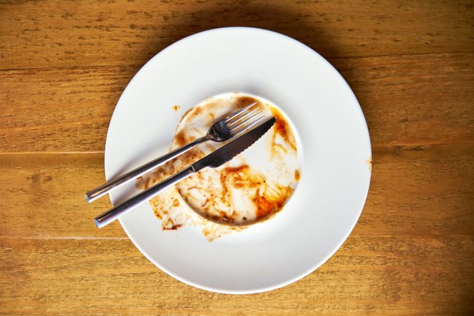 Forks arranged on a ceramic plate with sauce residue