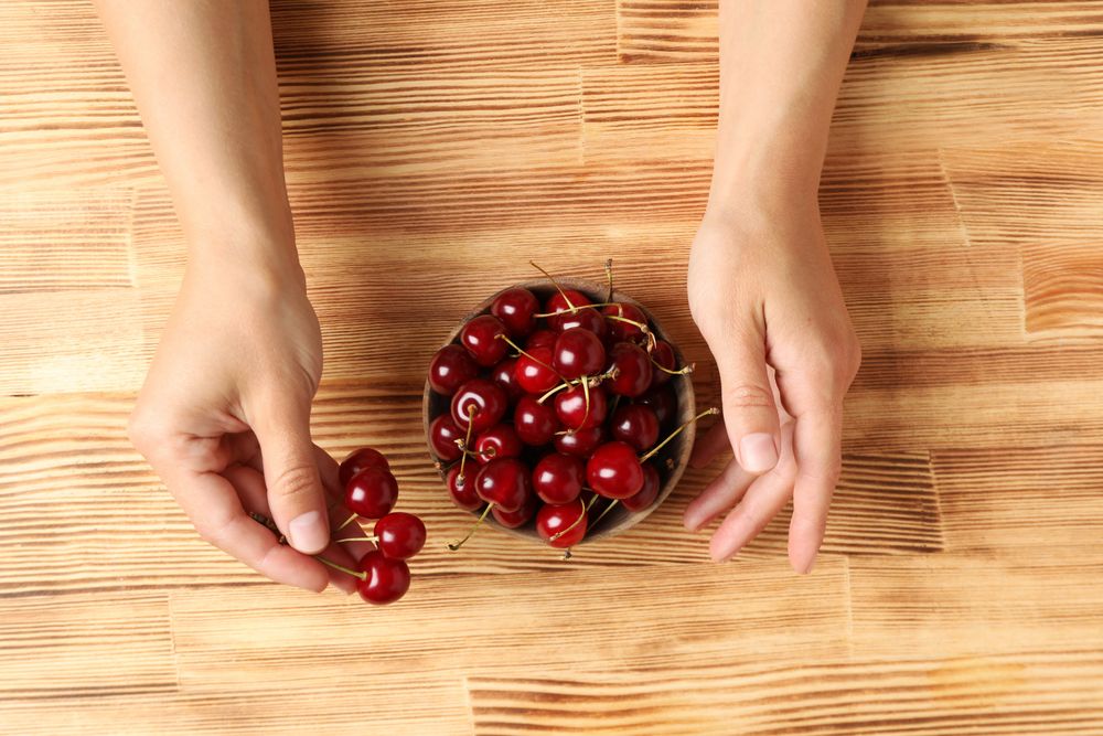 Ripe cherry fruits in a bowl on a wooden background