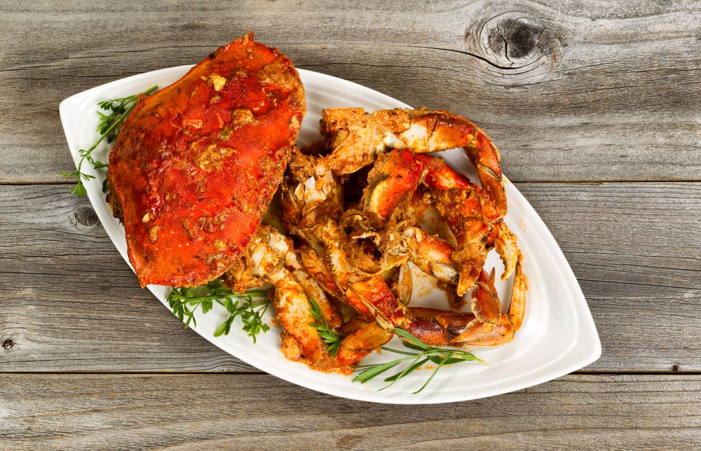 Spicy cooked crab ready to serve on plate with rustic wood underneath