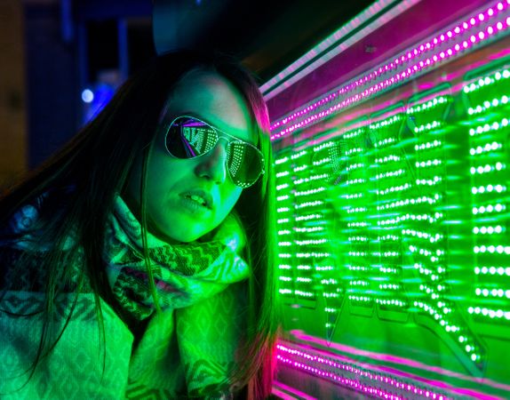 Stylish young woman near illuminated board