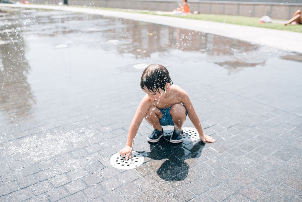 Kid standing in jet of fountain on street