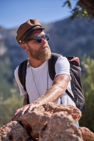 Bearded man putting hand on stone pile