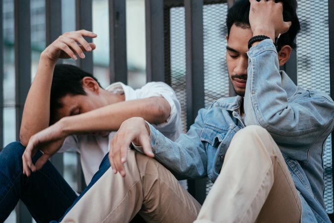 Two stressed Asian man sitting and holding their heads