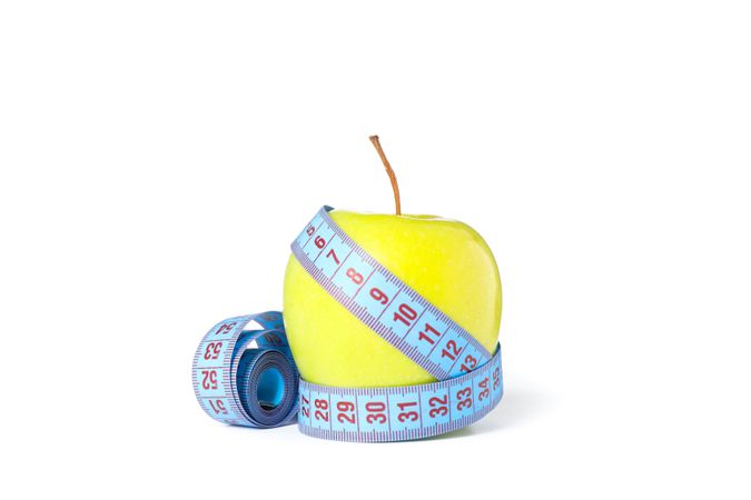Measuring tape and apple isolated on plain background