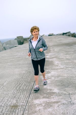 Older sportswoman walking by sea pier
