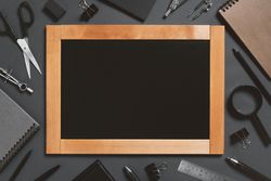 Writing board surrounded by stationary on dark background