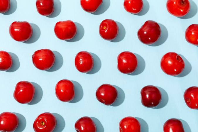 Flat lay with red cherry on blue background, top view