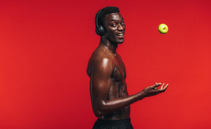 Athletic man in studio with apple and headphones