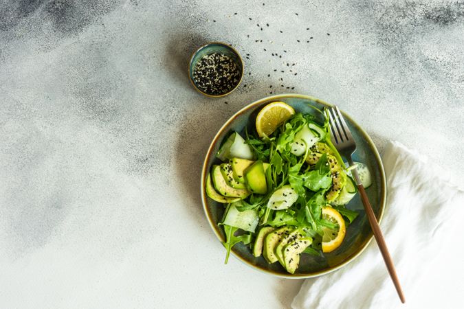 Top view of healthy vegetable salad with arugula and avocado with copy space