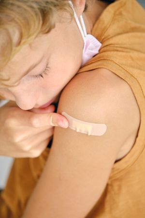Crop boy applying medical patch on shoulder