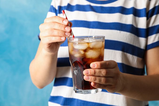 Female hands holding a glass with cola and tubule
