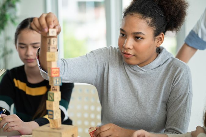 Two girls sitting in classroom, one with alphabet blocks