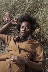 Black woman in brown laying on brown grass 5lKVM0