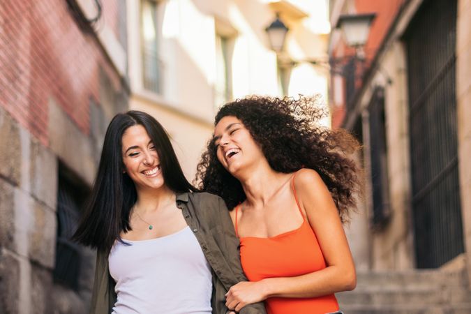 two young women going down street stairs smiling holding her hands and hugging