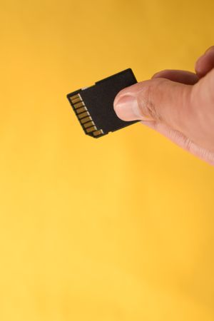 Hand holding SD card for data in yellow studio shoot
