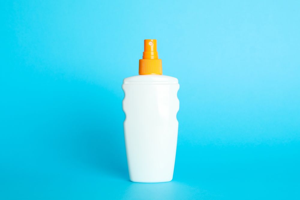 Sunscreen spray on color background, space for text