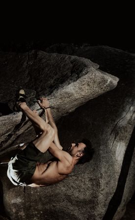 Man practicing rock climbing among large rocks in a forest