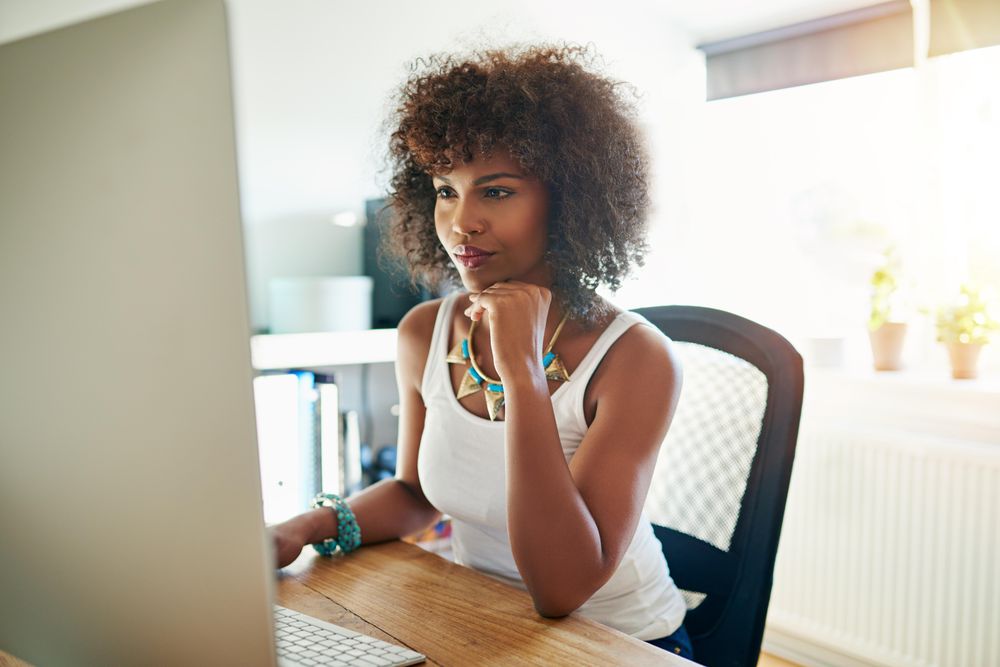 Female entrepreneur in bright office concentrating as she reads her computer monitor in the morning