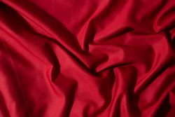 Crumpled wavy Red silky fabric background texture.