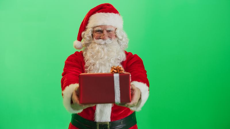 Studio Shot Isolated Mockup Template: Jolly Santa Claus Offering Beautifully Wrapped Gift To Children On Green Screen Chromakey Background. Concept Of Christmas, Holidays, New Year, Celebration