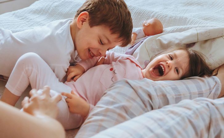 Closeup of happy boy and little girl playing in bed on a relaxed morning