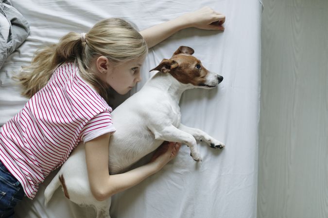 Young girl lying on bed with her dog with their eyes open