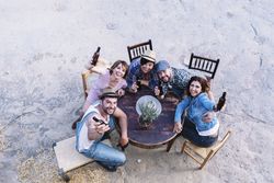 Looking down at a group of friends sitting around a table holding beers