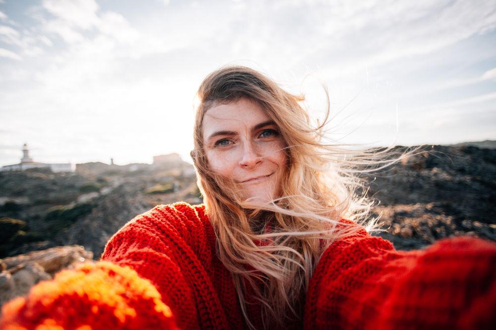 Woman in red sweater taking selfie on windy day
