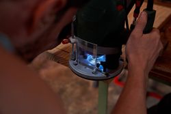 Crop male carpenter grinding wooden plank using special equipmen